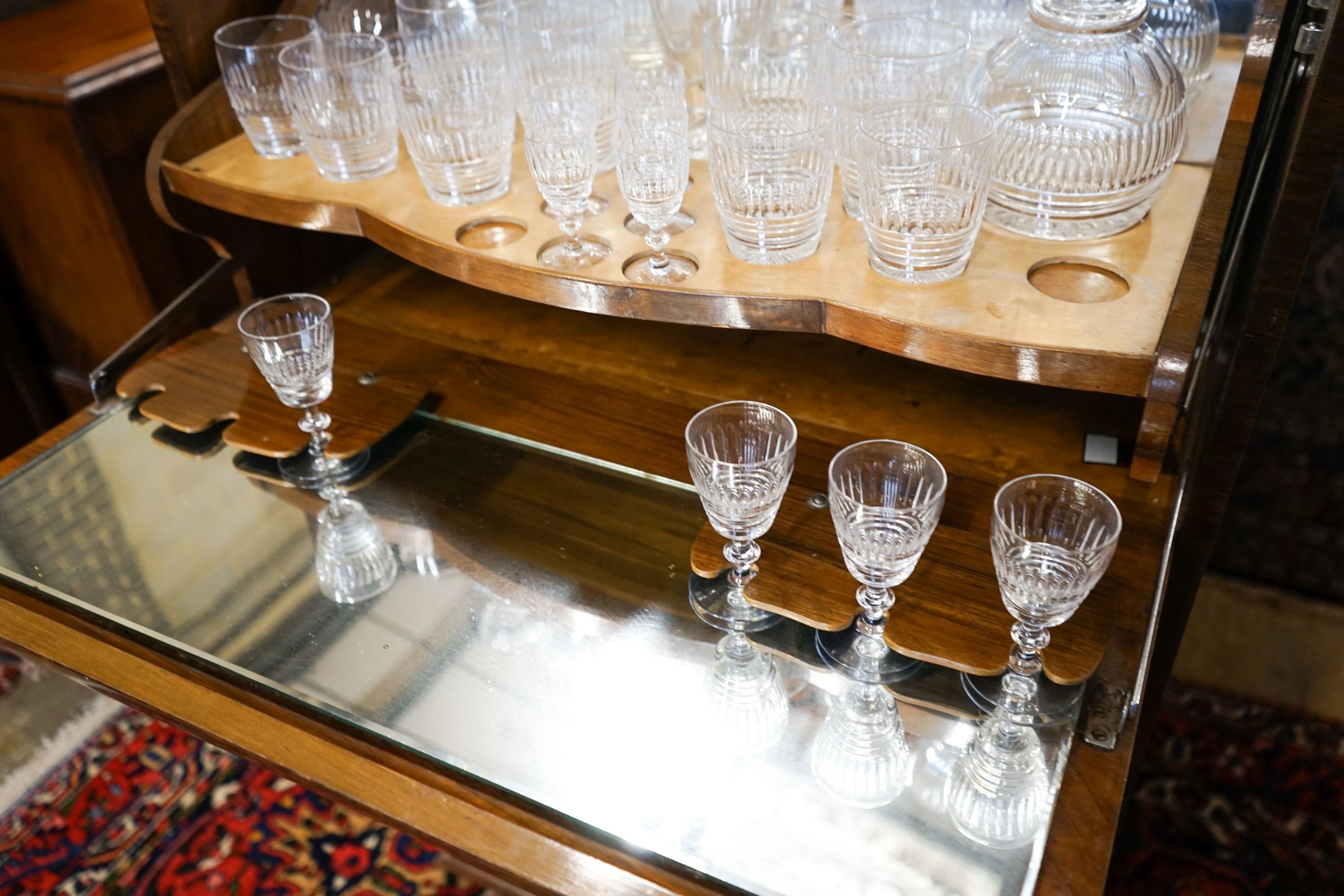 An Art Deco figured walnut and maple-lined cocktail cabinet, width 74cm, depth 41cm, height 121cm, containing a part suite of cut crystal table glass